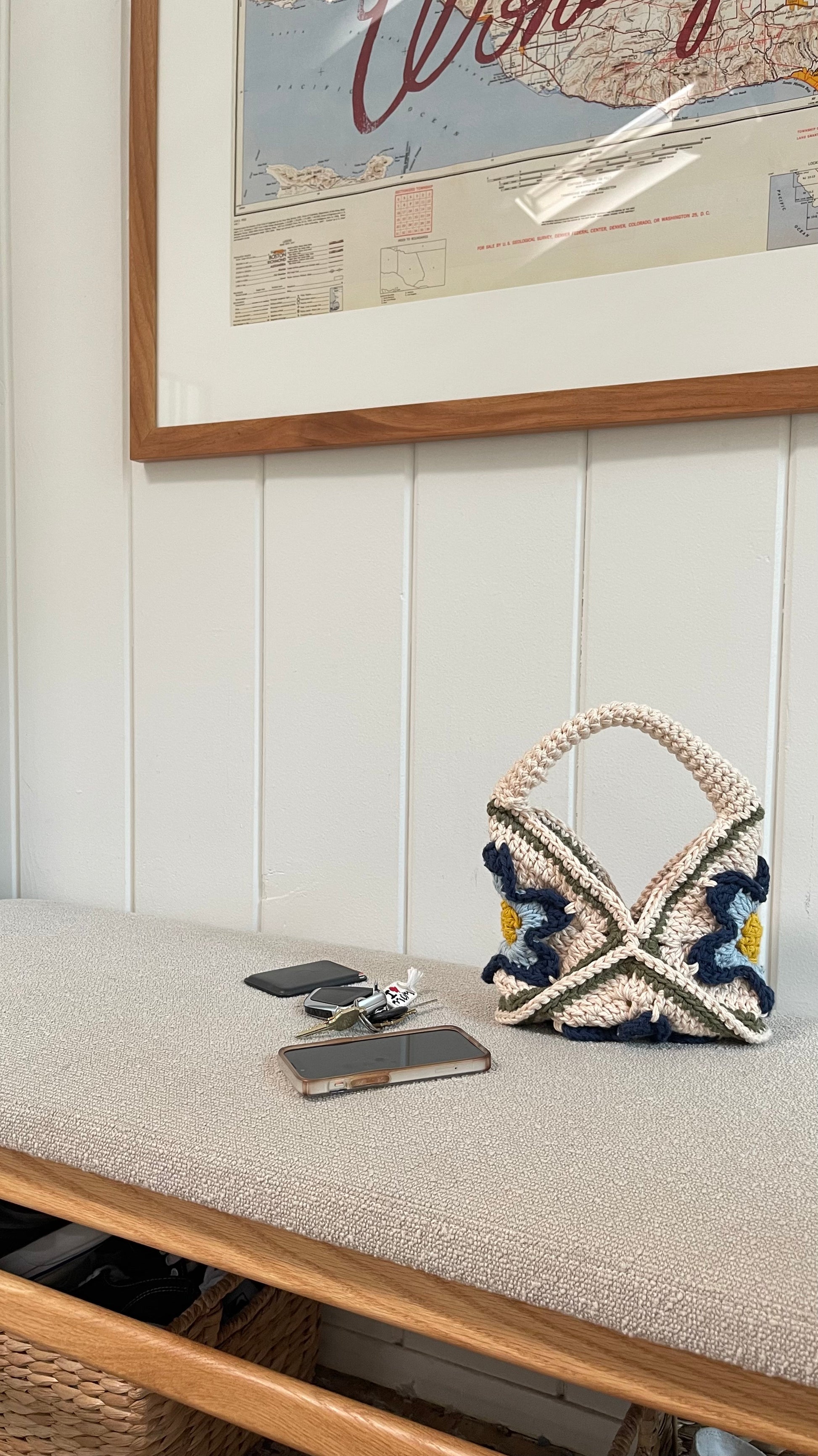 Lifestyle shot of a crocheted handbag in cream, yellow, baby blue and navy blue. 