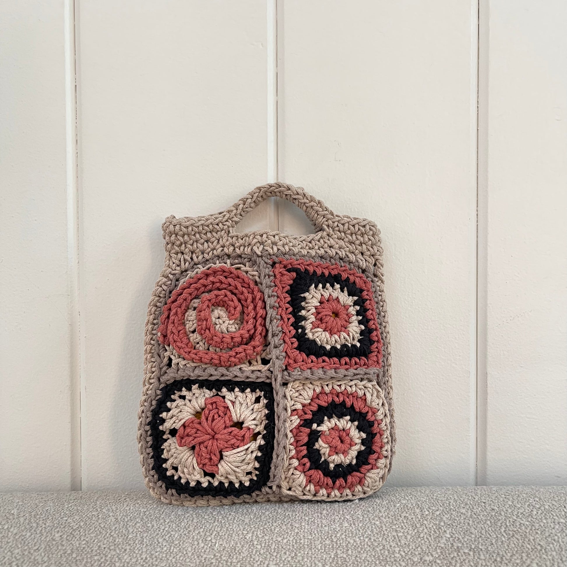 Photo of a crocheted granny square handbag in tan, grey, black and brick red. 