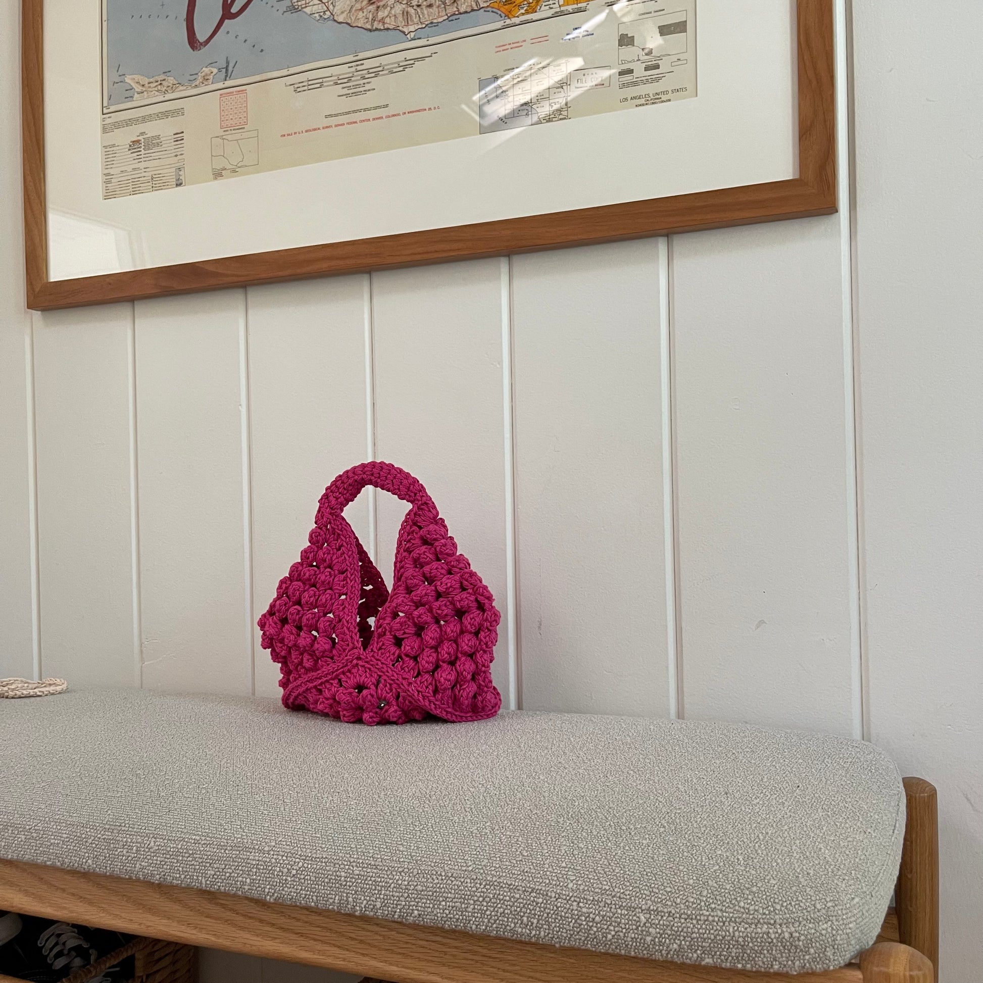 A lifestyle picture of a pink crocheted granny square handbag. 