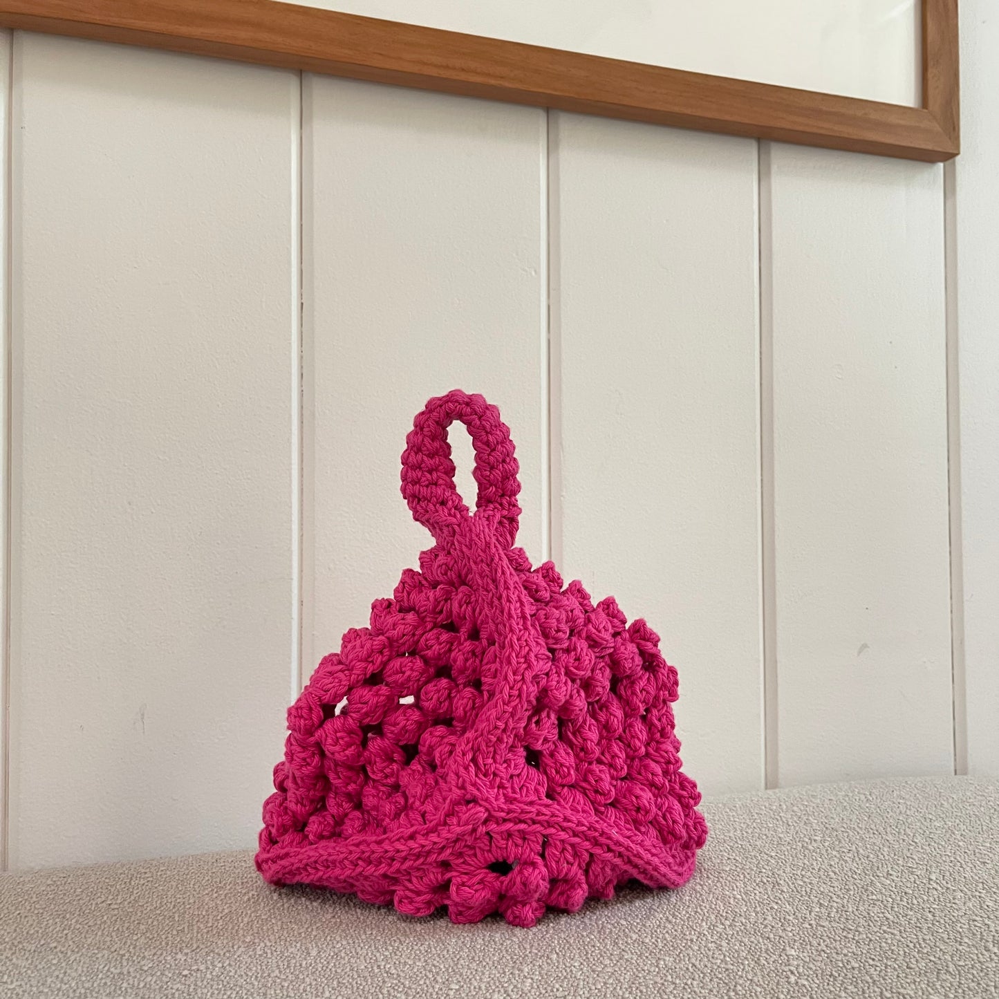 A pink crocheted granny square handbag. 