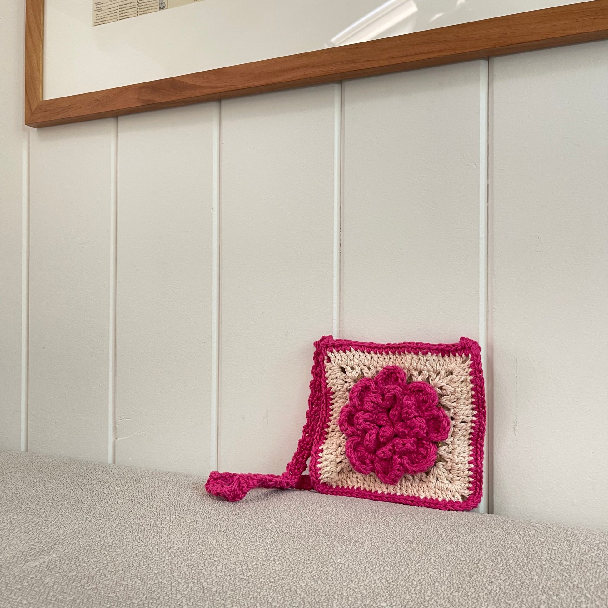 lifestyle photo of a crocheted granny square crossbody bag in pink and white. 