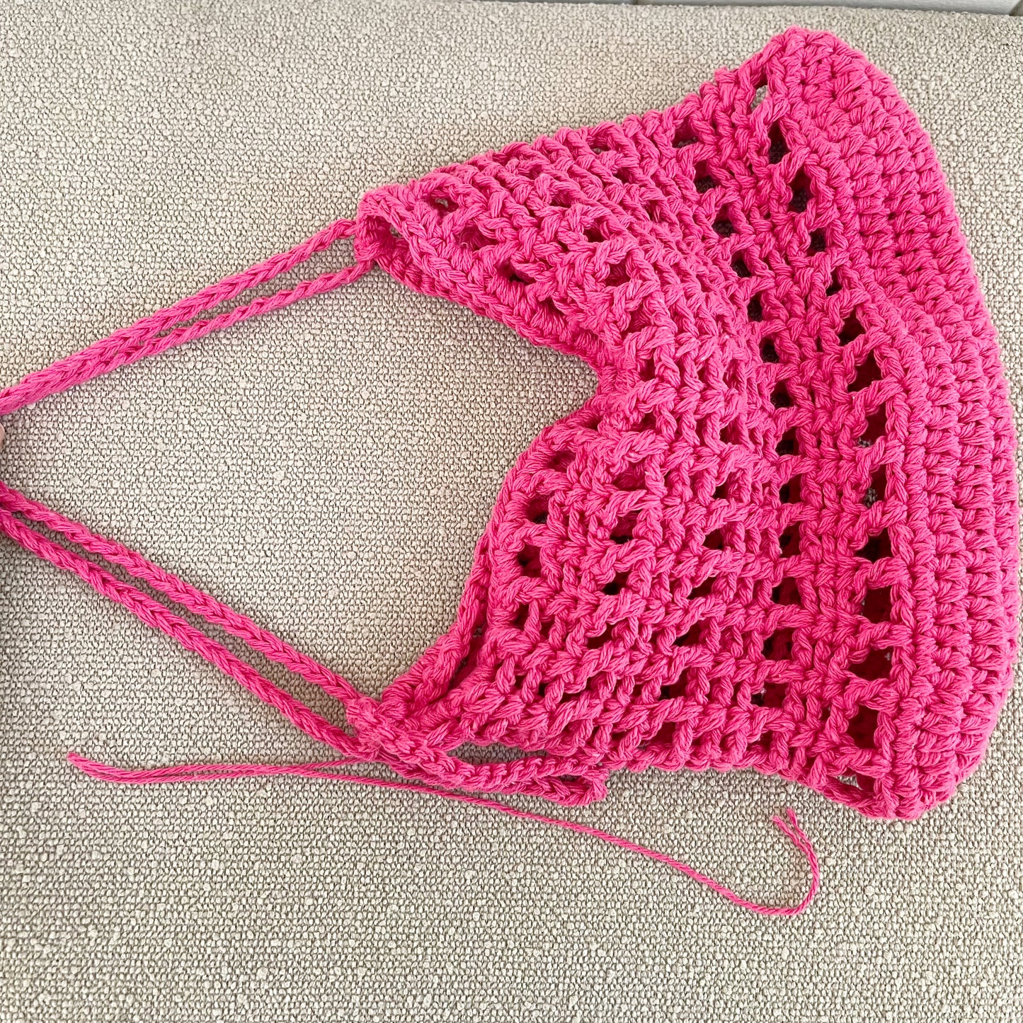 A closeup picture of a crochet mesh handbag in hot pink.  Measures 11" wide x 8" tall + a shoulder strap. Made of 100% cotton.   